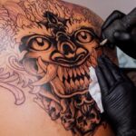 tattoo artist working on a back tattoo